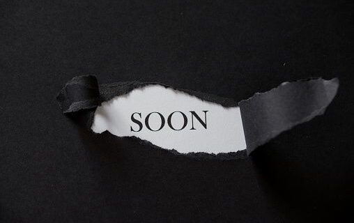 Word SOON printed on a white background with black torn paper.